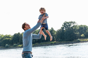 Family playing by river outdoors having fun and enjoying nature