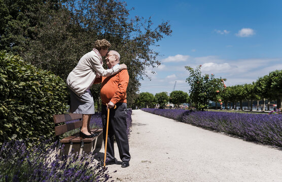 Happy couple sharing a kiss outdoors on a sunny day in the park - Powered by Adobe