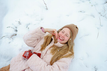 Blond woman smiling joyfully outdoors in winter snow wearing hat