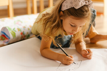 Child drawing on paper with concentration and creativity indoors
