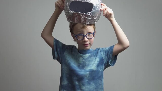 Little boy in glasses puts homemade space helmet on head