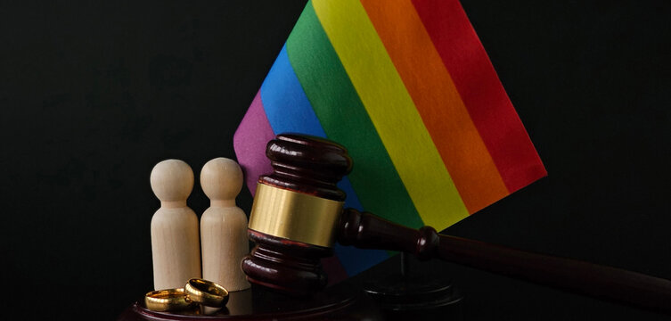 Two gold wedding rings and colored people figures with judge gavel concept