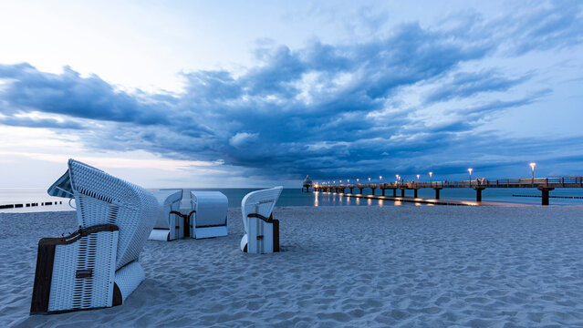 Fototapeta Beach chairs and pier at dusk on Zingst Baltic Sea coast Germany