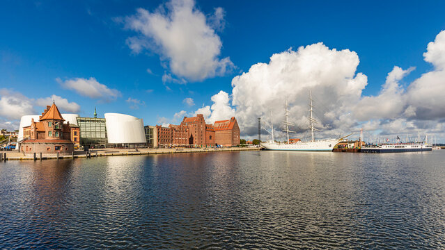 Stralsund harbor with Ozeanum aquarium and Gorch Fock 1 under blue sky