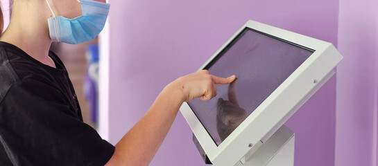 Young girl uses touch screen kiosk in public place