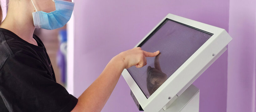 Young girl uses touch screen kiosk in public place