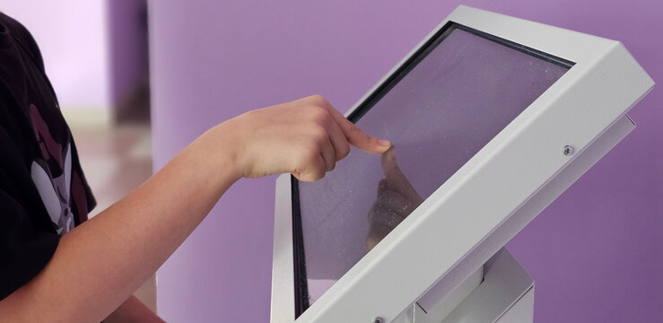 Teenager interacts with touch screen kiosk in purple room