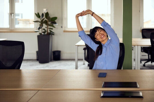 Woman Stretching At Desk In Modern Office For Relaxing Break