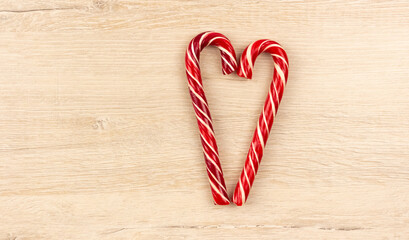 Heart made from Christmas candy canes on a wooden background
