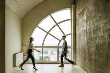 Realtor and client walking in modern apartment with large window