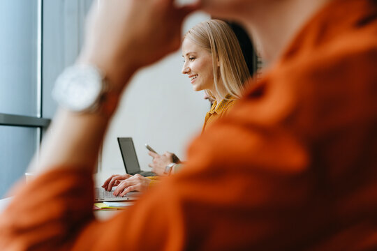 Business colleagues working together at office desk with laptops