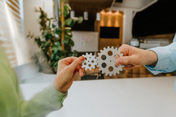 Business colleagues joining gears in office to symbolize team work