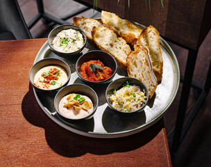 Delicious spread of dips served with fresh bread on a wooden table