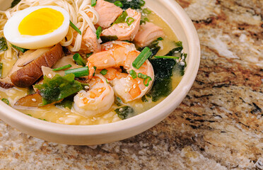 Delicious seafood noodle soup with egg and vegetables in a warm bowl
