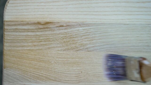 Wood absorbs enamel as brush glides across surface, securing protective layer for shine and durability. Coating highlights grain, ensuring refined and polished appearance