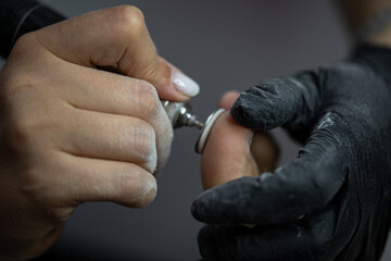 Electric file tool used during professional pedicure procedure to smooth toe skin in beauty salon