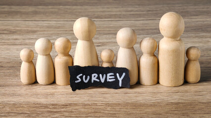 Survey concept with wooden peg dolls representing a diverse group and a handwritten note, symbolizing market research and data collection from a sample population.