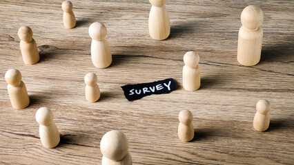 Survey concept with wooden peg dolls representing a diverse group and a handwritten note, symbolizing market research and data collection from a sample population.
