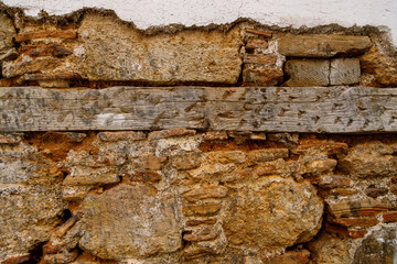 Close-up of a weathered stone and wood wall with visible textures and earthy tones, showcasing rustic construction and natural aging.