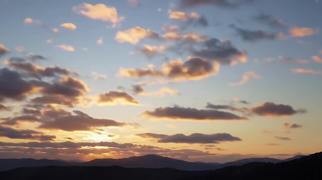 Serene sunset over rolling hills with dramatic clouds and warm golden light stretching across the horizon