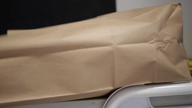 Kraft paper bag unfolding from flat folded shape, producing crisp packaging sound, illustrating food delivery preparation, eco-conscious shopping concept and modern sustainable packaging use