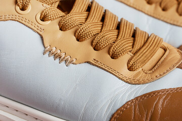 Close-up view of a stylish comfortable two-tone blue leather sneaker with intricate craft stitching and brown laces representing craftsmanship quality of leatherwork for active footwear fashion