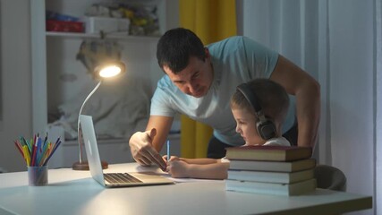 Man and boy working on laptop. Father learning distance with laptop. Child helps study on a table in the evening. Lifestyle a man and a young boy using a laptop.