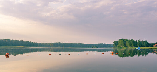 Calm lake with a few orange buoys floating on the water