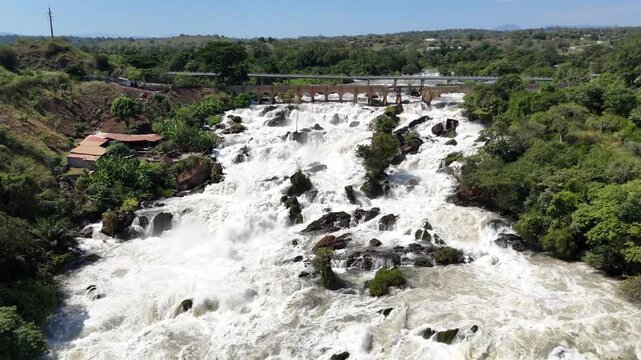 Majestic aerial view of Binga Falls in Angola, showing multiple whitewater cascades flowing down rocky cliffs surrounded by dense green tropical forest.