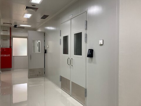 Brightly lit, pristine corridor with multiple sealed doors leading to specialized areas within a modern scientific or industrial facility, emphasizing sterility and controlled access