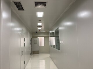A long, sterile white corridor in a modern scientific laboratory or pharmaceutical manufacturing facility with cleanroom technology