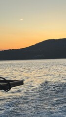 Sunset over a traditional Greek island with whitewashed houses, blue domed roofs, and narrow stone streets. Warm golden and orange light reflecting on the Aegean Sea, creating a peaceful and romantic 