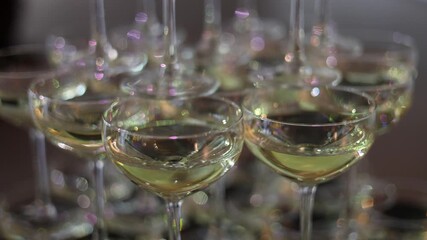 A close-up view of multiple coupe glasses filled with white wine, with shimmering reflections and soft focus background. Ideal for festive or celebratory themes