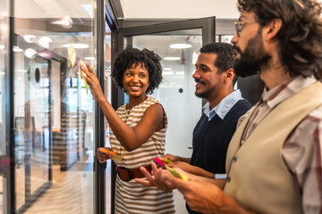 Coworkers team brainstorming ideas with sticky notes on glass wall