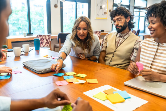 Coworking colleagues brainstorming ideas with sticky notes during meeting