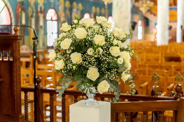 Beautiful white rose bouquet displayed in a church setting during a wedding ceremony