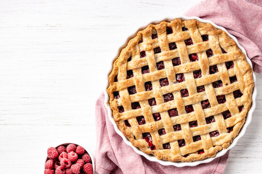 Classic American raspberry pie with napkin on white background.
