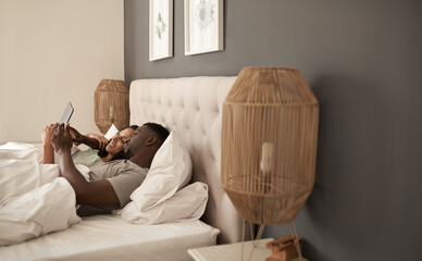 Smiling multiracial couple using a digital tablet in bed
