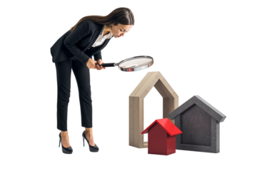 Female businesswoman closely inspecting house-shaped property models using magnifying glass, isolated on white background, real estate concept