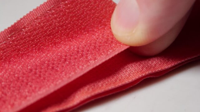 Pink Velcro Strap separating with sharp rustling sound as hook and loop surfaces pull apart, revealing textured fastening details, with close-up focus on sewing supplies, DIY use and fabric hardware