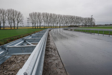 New guardrails beside a road in the Dutch polder during rainy weather