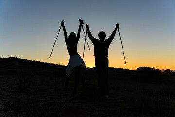 Senior couple celebrating nordic walking success at sunset
