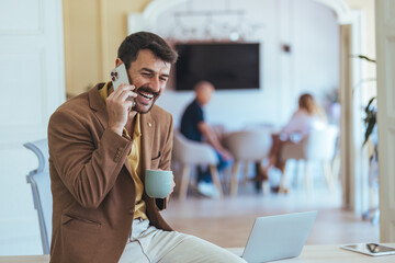 Smiling Man On Phone In Cozy Café With Laptop And Coffee Cup