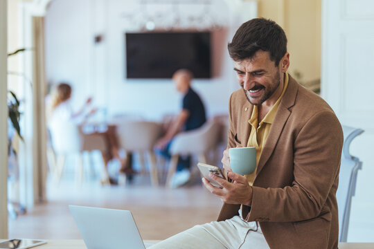 Professional Man in Brown Blazer Using Phone and Mug in a Modern Office Setting