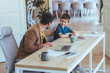 Father And Son At A Bright Home Office Desk With Laptop, Learning And Collaboration