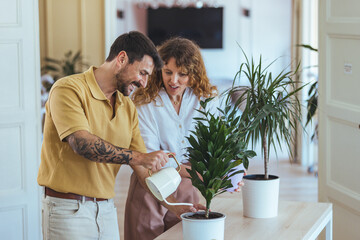 Happy Couple Watering Indoor Plants Together in Bright Home Interior