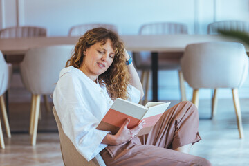 Relaxed Woman Reading a Book in a Modern Office Lounge Space