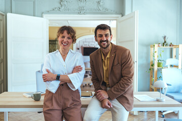 Friendly Team Of Two Colleagues In A Modern Office Smiling At The Desk