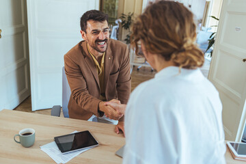 Friendly Business Handshake During a Meeting in a Bright Modern Office With Coffee and Tablet