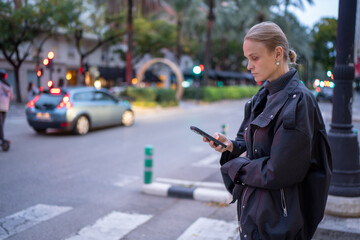 Woman using smartphone at city crosswalk